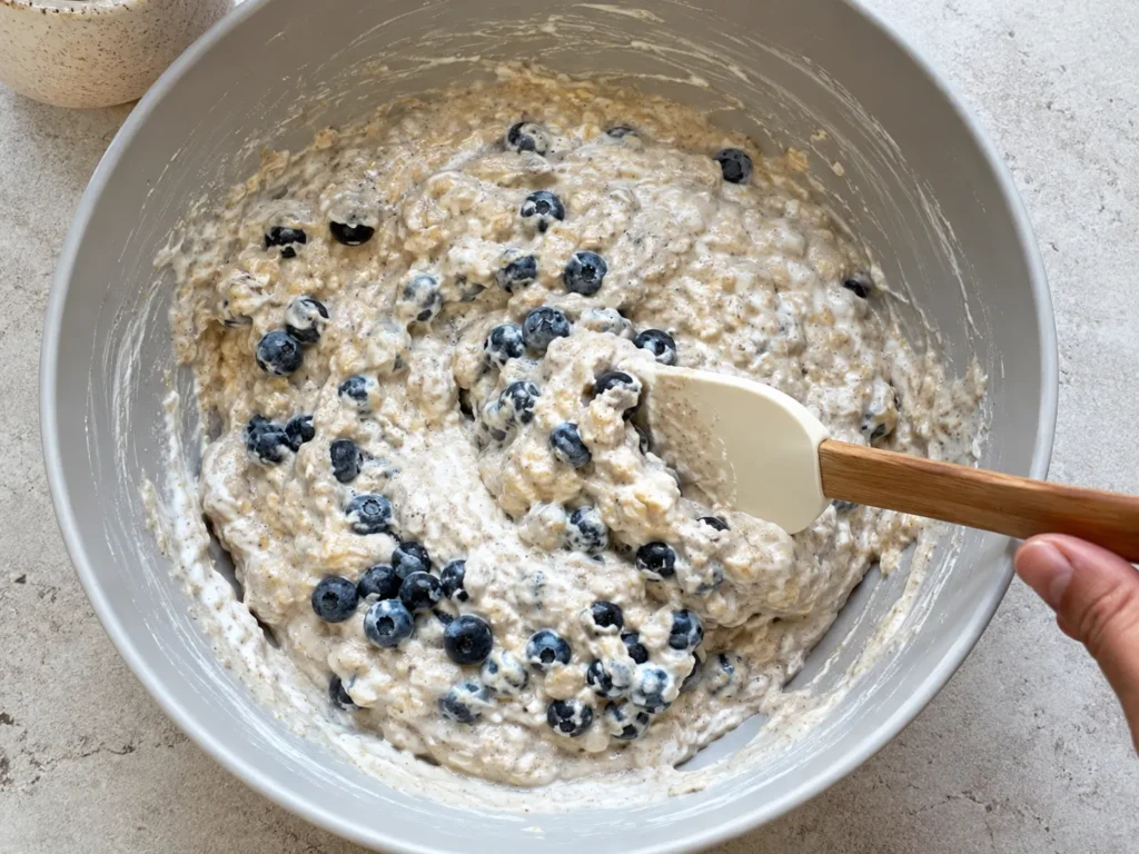 Thick batter with oats and blueberries being mixed for a cottage cheese breakfast bake