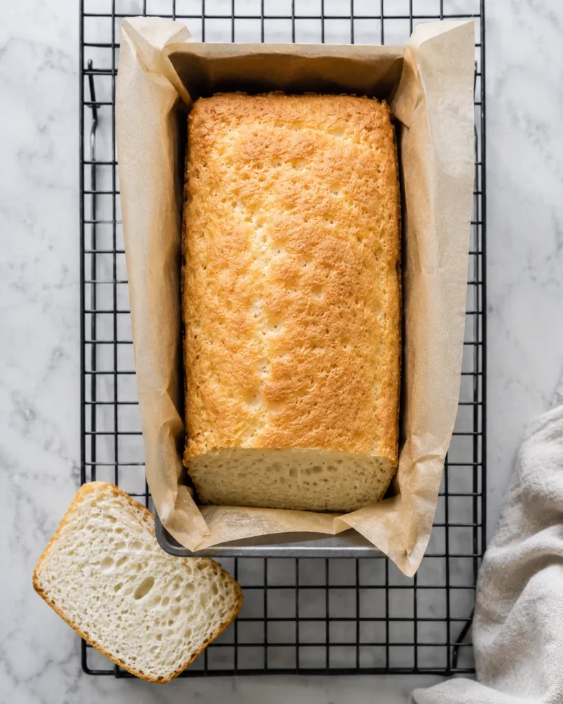 Zero-carb yogurt bread baked in a parchment-lined loaf pan with one airy slice removed